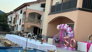 Un espace de restauration en plein air, avec des tables dressées pour une fête, décoré de fleurs et d’un grand ballon en forme de « 50 ».