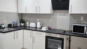 A modern kitchen with white cabinets, a black countertop, a microwave, a toaster, and a kettle.