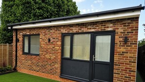 A brick house with two large windows and a black door.