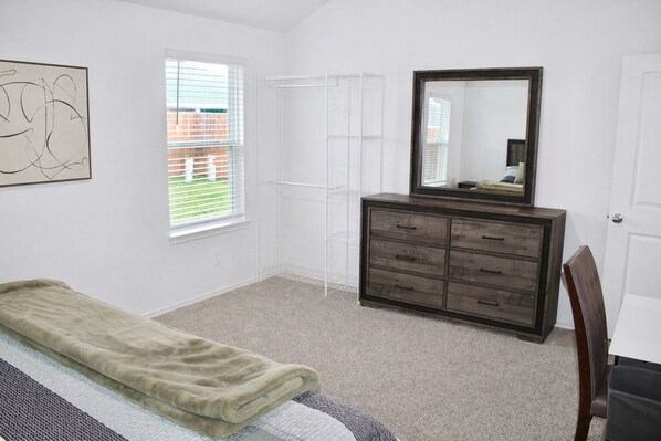 Un dormitorio con cama, cómoda, espejo y ventana.