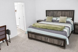 Une chambre à coucher avec un lit, des tables de chevet, une chaise et une porte.