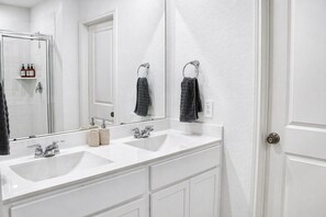 A bathroom with two sinks, a large mirror, and a towel rack. - Modern 3 BR New House with Grill and Games (Pattison)