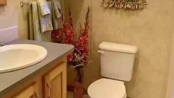 A bathroom with a sink, toilet, wooden cabinets, and a window with curtains.