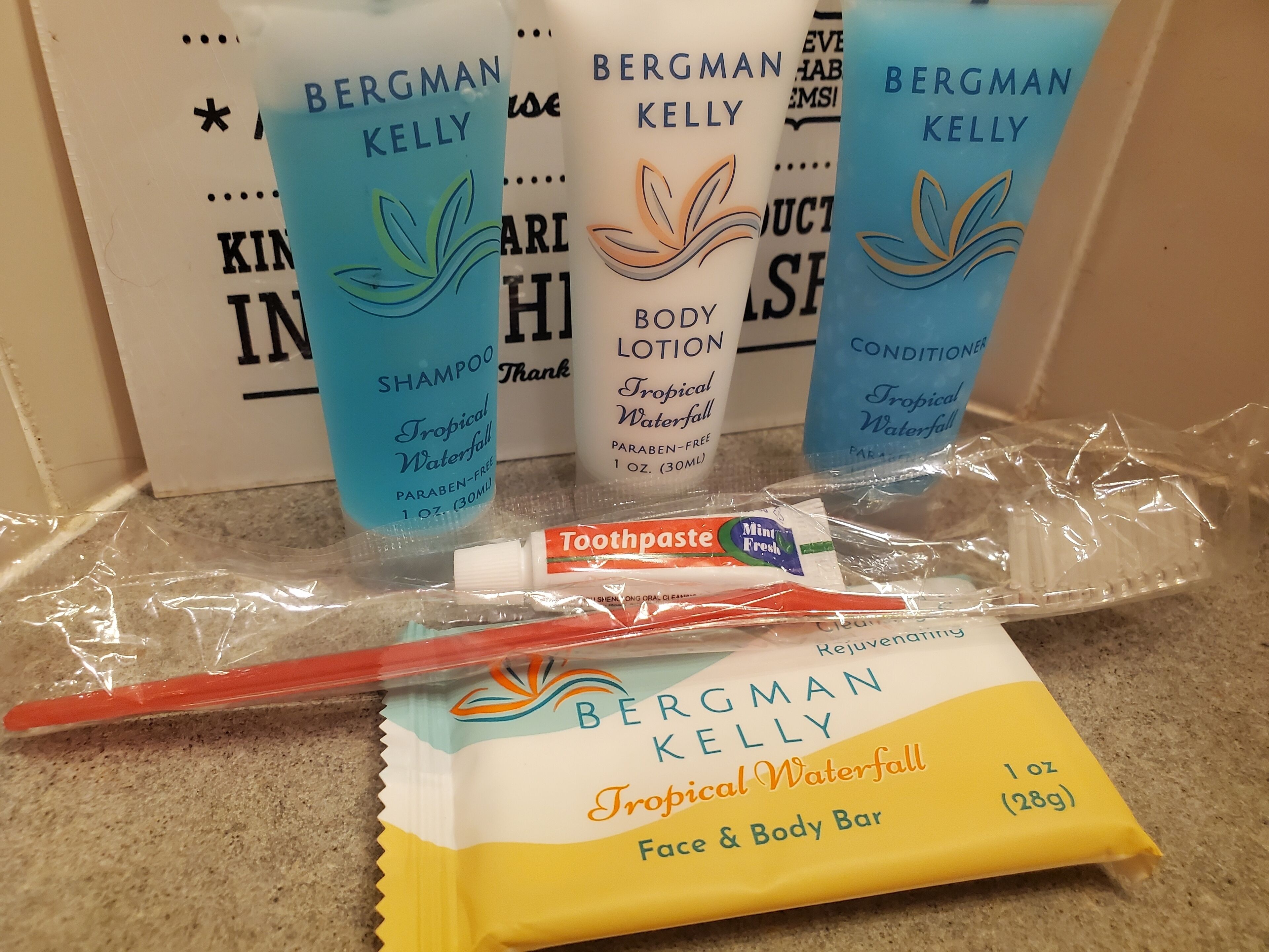 A collection of Bergman Kelly personal care products including shampoo, body lotion, toothpaste, and a face & body bar.