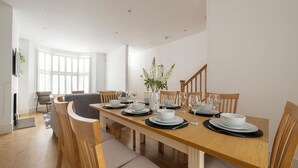 Comedor con mesa de madera dispuesta para cuatro personas, rodeada de sillas de madera.