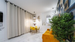 Uma sala moderna com um sofá amarelo, uma área de jantar com cadeiras amarelas e uma grande planta verde.