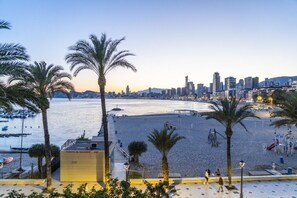 A beach with palm trees, a city skyline in the background, and a boardwalk with benches. - Brisas del Poniente-Deluxe Room Ocean View (Benidorm)