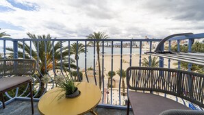 A balcony with a view of a beach, palm trees, and a cityscape. - Brisas del Poniente-Deluxe Room Ocean View (Benidorm)