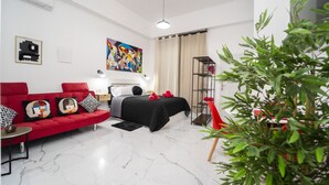 Una sala moderna con un sofá rojo, una cama negra y una planta.