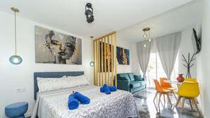 A modern hotel room with a large bed, a seating area with chairs, and artwork on the walls. - Brisas del Poniente- Apt-Studio with sea views (Benidorm)