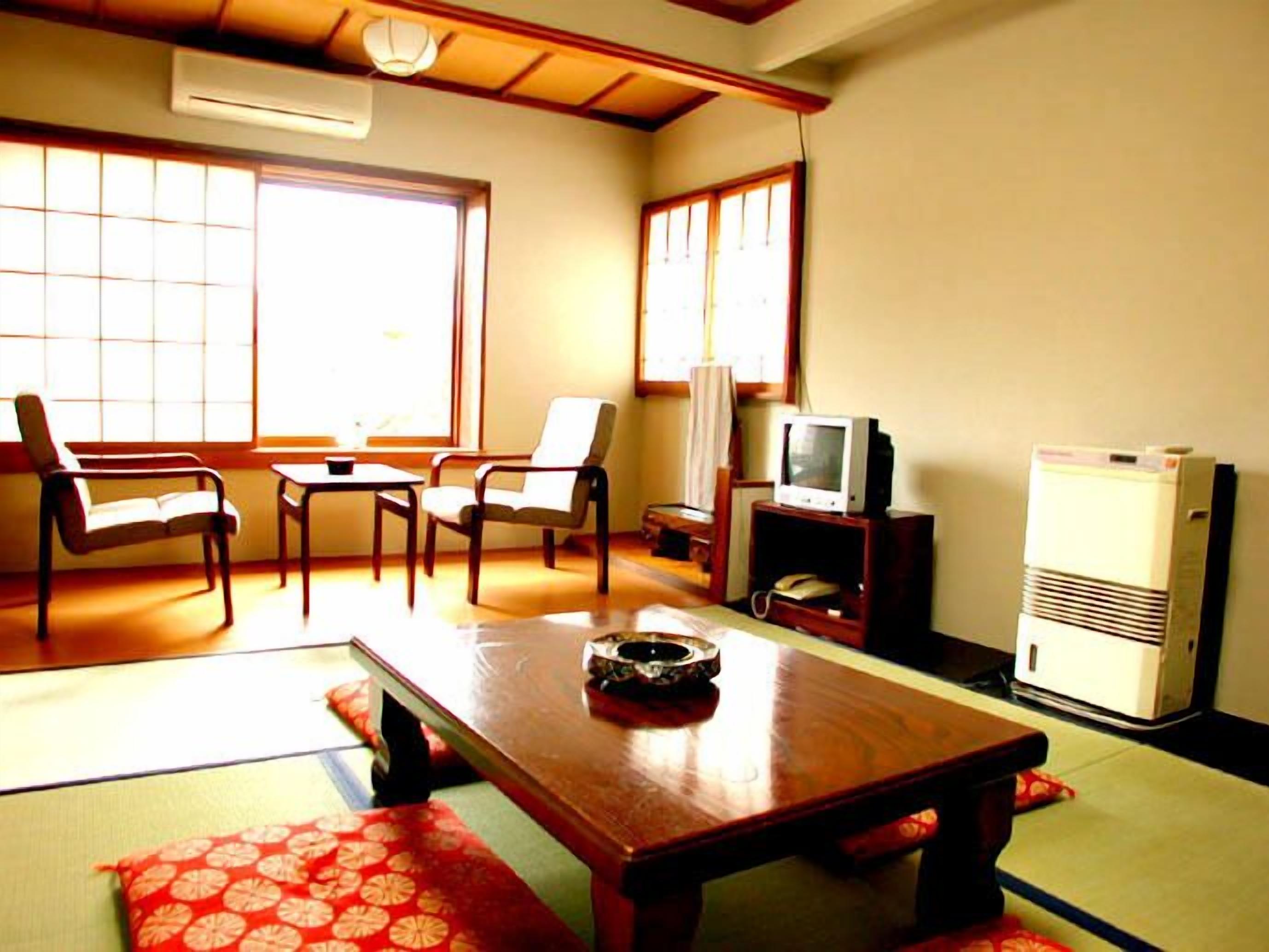 Una habitación tradicional japonesa con suelo de tatami, una mesa de madera baja y un televisor.
