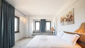 Habitación de hotel con una cama grande, un sofá cama, una lámpara y un cuadro en la pared.