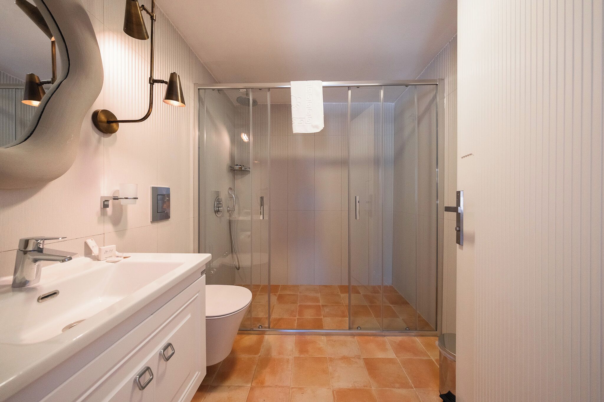 A modern bathroom with a glass-enclosed shower, a white sink, and a toilet.