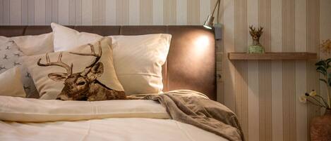 Un lit bien fait, avec une tête de lit, une lampe de chevet et des coussins décoratifs.