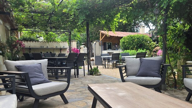 Un espace extérieur aménagé avec un sol en pierre, des tables et des chaises.