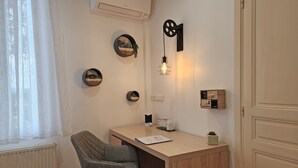 A small, well-lit room with a desk, chair, and various wall decorations including framed pictures and a wall-mounted light fixture. - Chambre Romarin - Domaine à l'Aise (Saint-Pargoire)