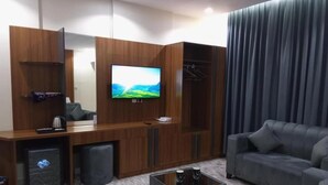 A modern living room with a sofa, a coffee table, a TV mounted on a wooden cabinet, and a wardrobe with a mirror. - Ansam Taiba Hotel (Madinah)