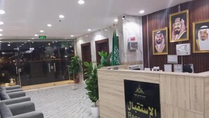 A reception area with a marble floor, a reception desk, and framed portraits on the wall. - Ansam Taiba Hotel (Madinah)