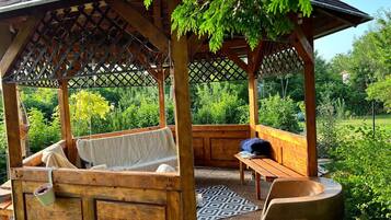 Ein hölzerner Pavillon mit gepolsterten Sitzgelegenheiten, einer Bank und einem Tisch.