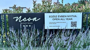 Señalización de 'Ucon Apartment' con un código QR e información que indica que está abierto todo el año.