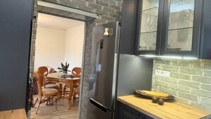 Una cocina compacta con armarios oscuros, un refrigerador de acero inoxidable y una encimera de madera.