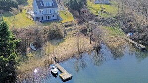 A house with a dock extending into a body of water, surrounded by trees and a grassy area. - House Langsee 2 (Kosel)