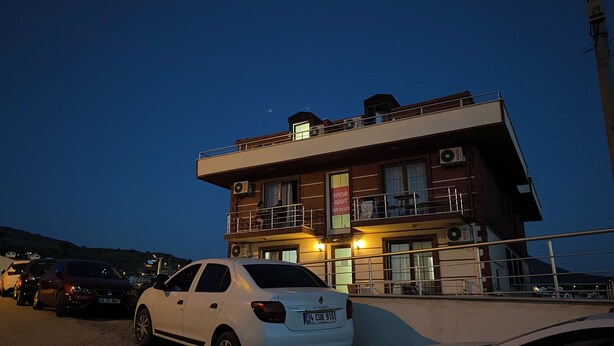 A multi-story building with balconies, air conditioning units, and a sign indicating it is an apartment building. - SELÇUK APART (Gökçeada)