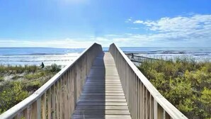 A wooden boardwalk leading to the beach with a clear sky and ocean in the background. - Salty Sea Wishes - Ocean Views, Beach Access, Family Vibes (Galveston)