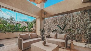 A spacious living area with a stone wall, a large window, and a view of the outside. - Arbor at Caivama (Sayulita)