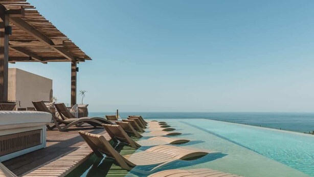 A poolside area with lounge chairs and a wooden pergola overlooking the ocean. - Arbor at Caivama (Sayulita)