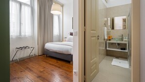 A bedroom with a bed, a bedside table, a lamp, and a window with curtains. - GuestReady - Zenith Building - Room 001 (Porto)