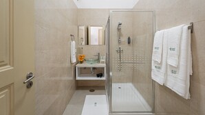 A modern bathroom with a glass-enclosed shower, a white sink with a glass bowl, and a mirror above the sink. - GuestReady - Zenith Building - Room 001 (Porto)
