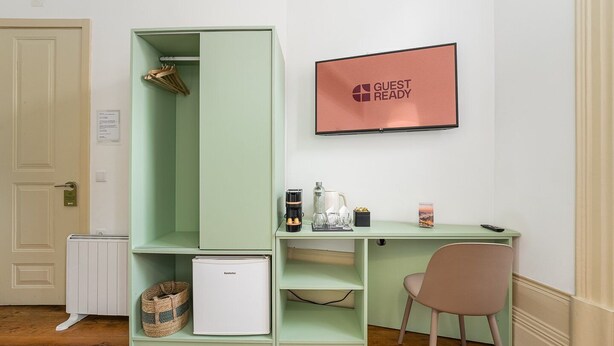 A compact room with a kitchenette, a small refrigerator, a coffee maker, and a framed sign on the wall. - GuestReady - Zenith Building - Room 001 (Porto)