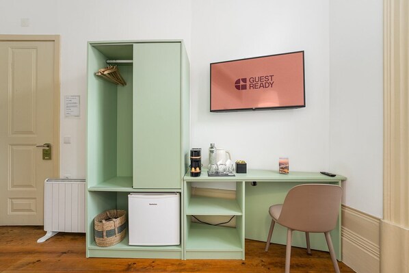 A compact room with a kitchenette, a small refrigerator, a coffee maker, and a framed sign on the wall.