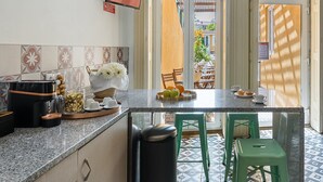 A kitchen with a granite countertop, a coffee machine, and a bowl of flowers. - GuestReady - Zenith Building - Room 001 (Porto)