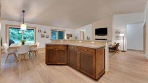 Una cocina amplia con una isla grande, armarios de madera y un comedor con sillas.