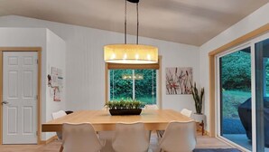 Un comedor moderno con una mesa de madera, sillas blancas y una lámpara colgante.