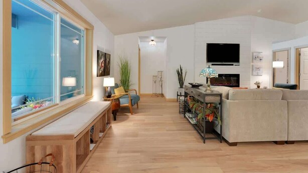 Una sala de estar moderna con un ventanal grande, un sofá, un televisor y un banco de madera.