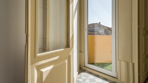 Ein Zimmer mit großem Fenster, einer Tür und einem gefliesten Boden.