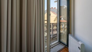 A room with a sliding glass door leading to a balcony with a metal railing. - GuestReady - Zenith Building - Room 102 (Porto)