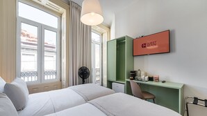 A hotel room with a bed, a desk, a chair, a TV, and a window with curtains. - GuestReady - Zenith Building - Room 102 (Porto)