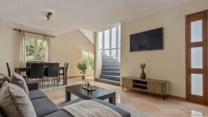 Ein modernes Wohnzimmer mit einer Couch, einem Couchtisch und einem Essbereich mit Stühlen und einem Tisch.