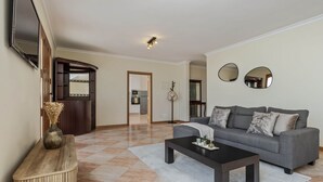 Ein Wohnzimmer mit grauem Sofa, einem schwarzen Couchtisch und einer Holztruhe mit einer Vase.