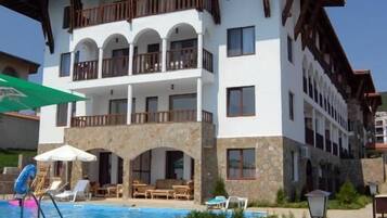 A multi-story hotel with balconies, a swimming pool, and outdoor seating.