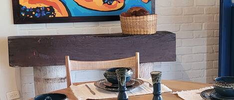 Una mesa de comedor con vajilla azul y negra, un cuenco decorativo y un cuadro de papaya en la pared de arriba.