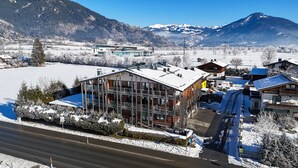 A modern building with large windows, a ski lift, and a snowy mountain backdrop.