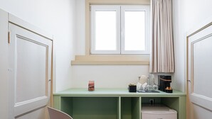A compact room with a green desk, a small refrigerator, a window with curtains, and a chair. - GuestReady - Zenith Building - Room 201 (Porto)