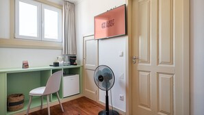 A room with a desk, chair, and a standing fan. There is a 'GUEST READY' sign on the wall. - GuestReady - Zenith Building - Room 201 (Porto)