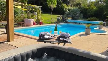 Boblebad med træterrasse, swimmingpool og pergola med solpaneler.