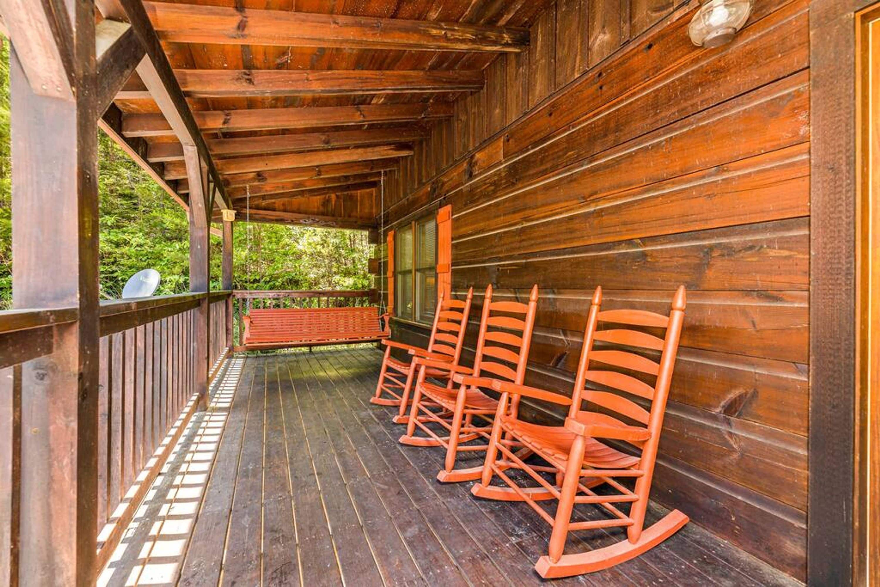 Eine hölzerne Veranda mit Schaukelstühlen, eine Holzterrasse und Blick ins Grüne.